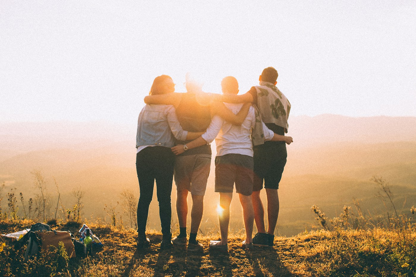 Four friends standing together outdoors in the evening sun